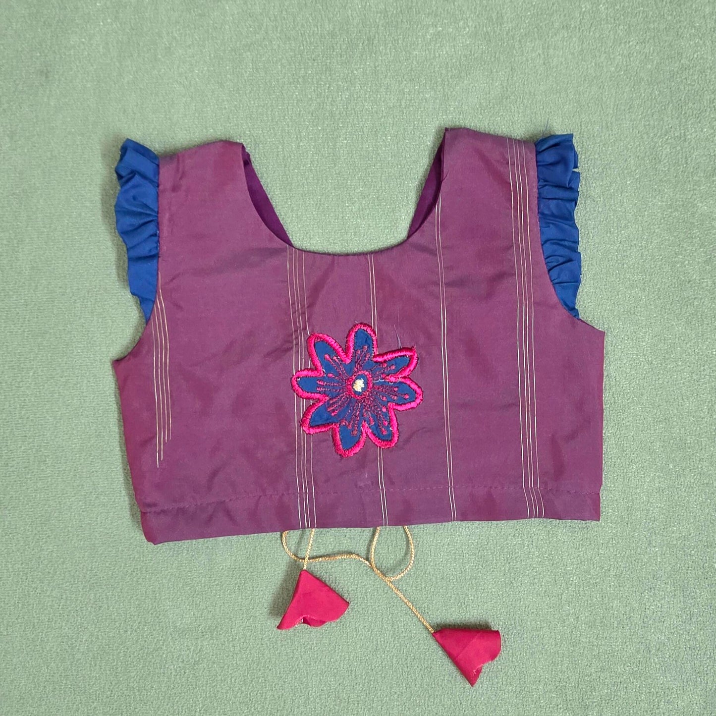 Purple blouse with floral embroidery on a green background