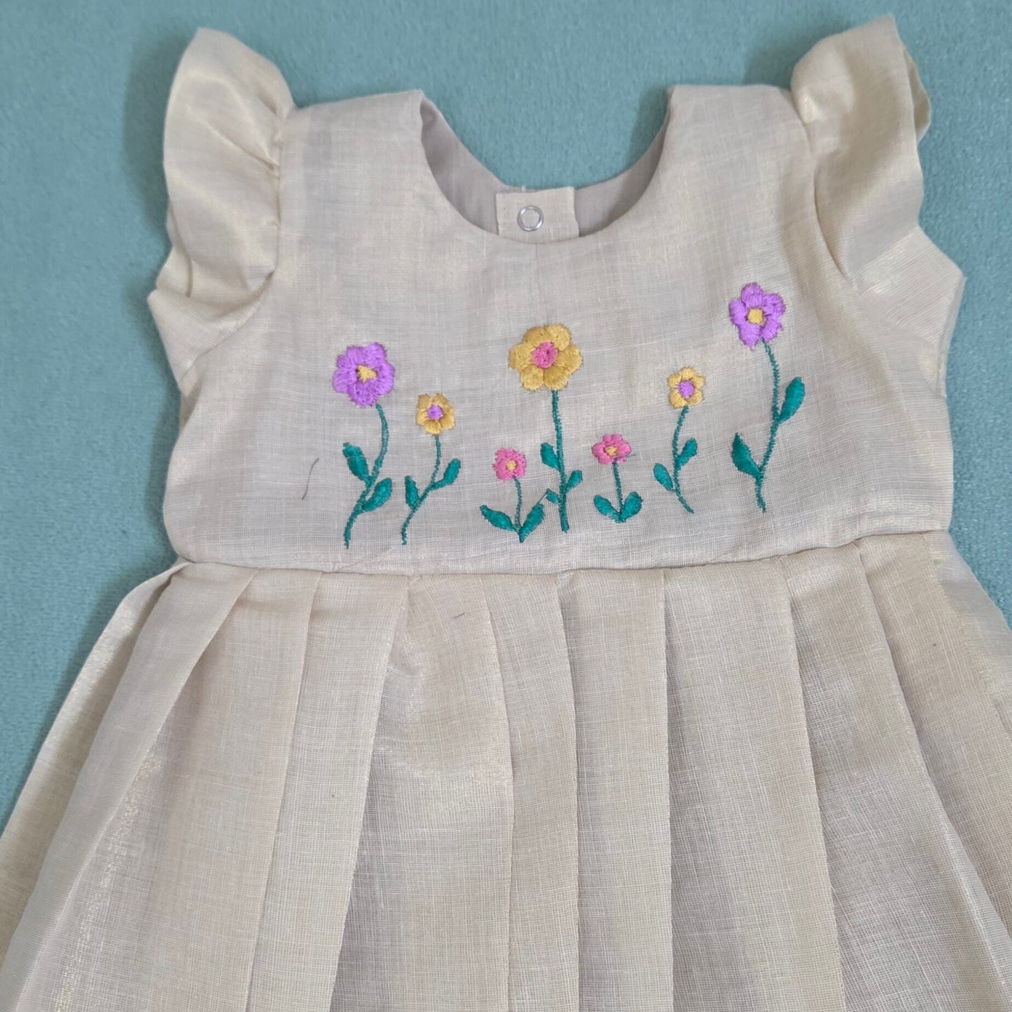 Onam girls' frock with floral embroidery and kasavu border.