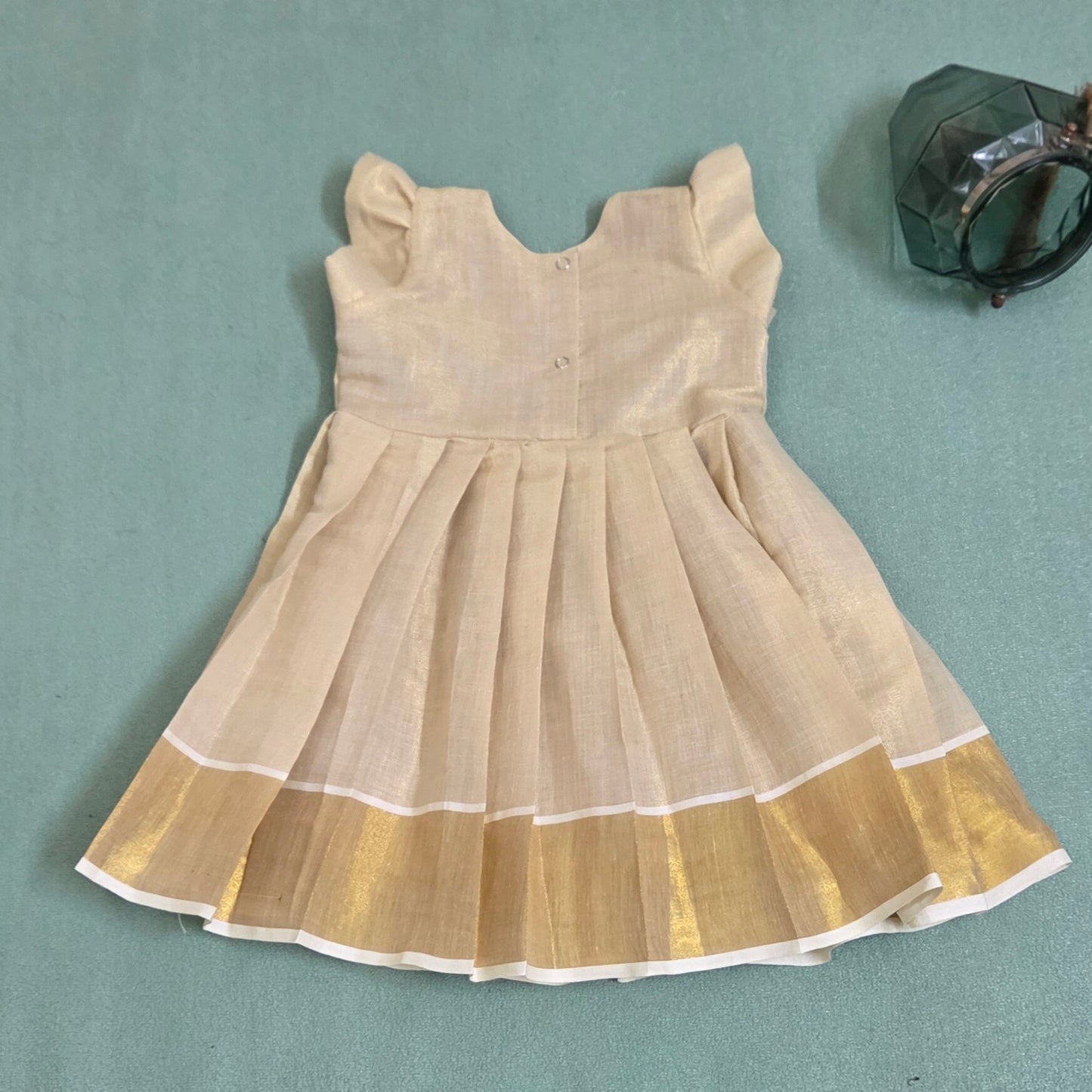 Backside view of Onam girls' frock with floral embroidery and kasavu border