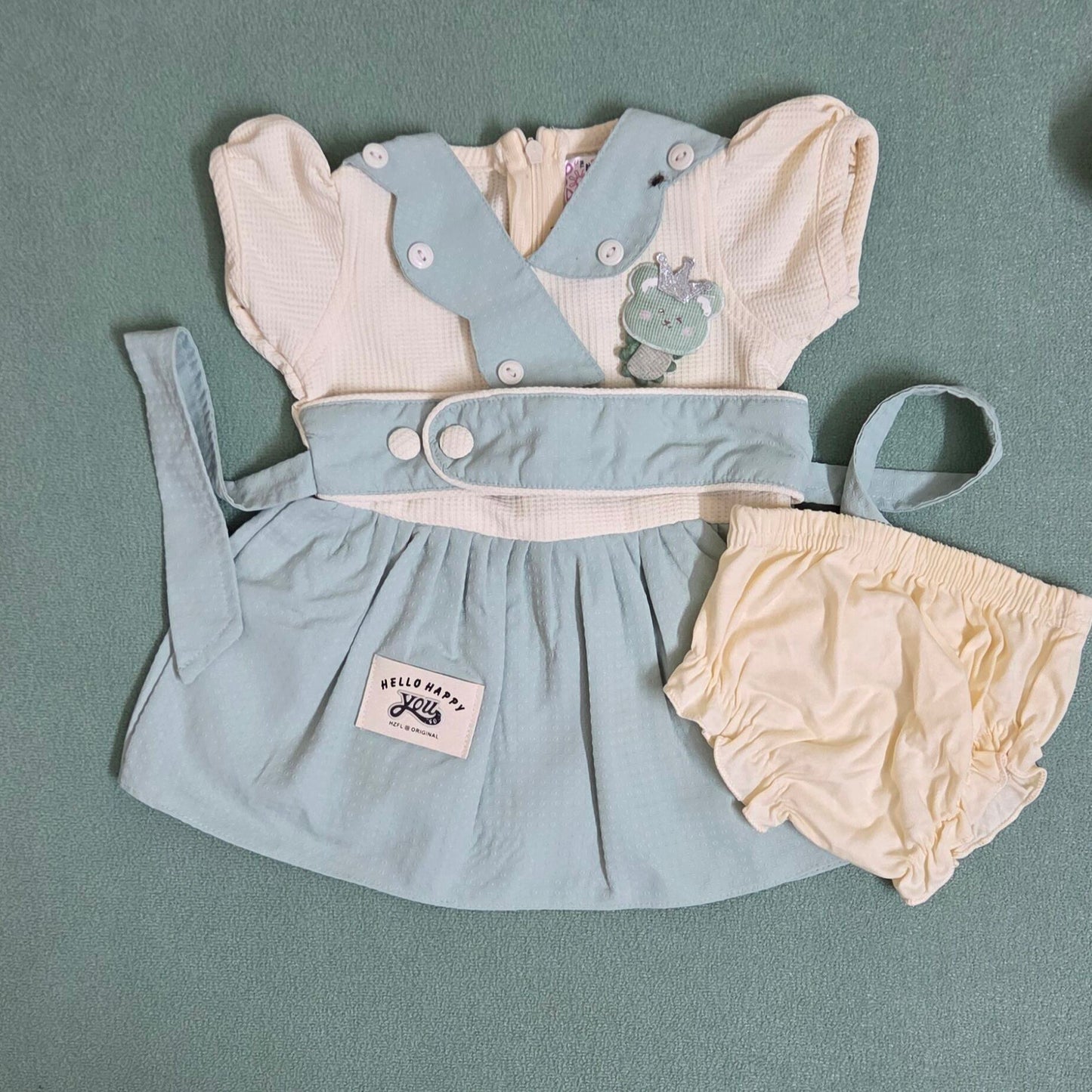 Baby outfit with light blue dress and bloomers on a gray background