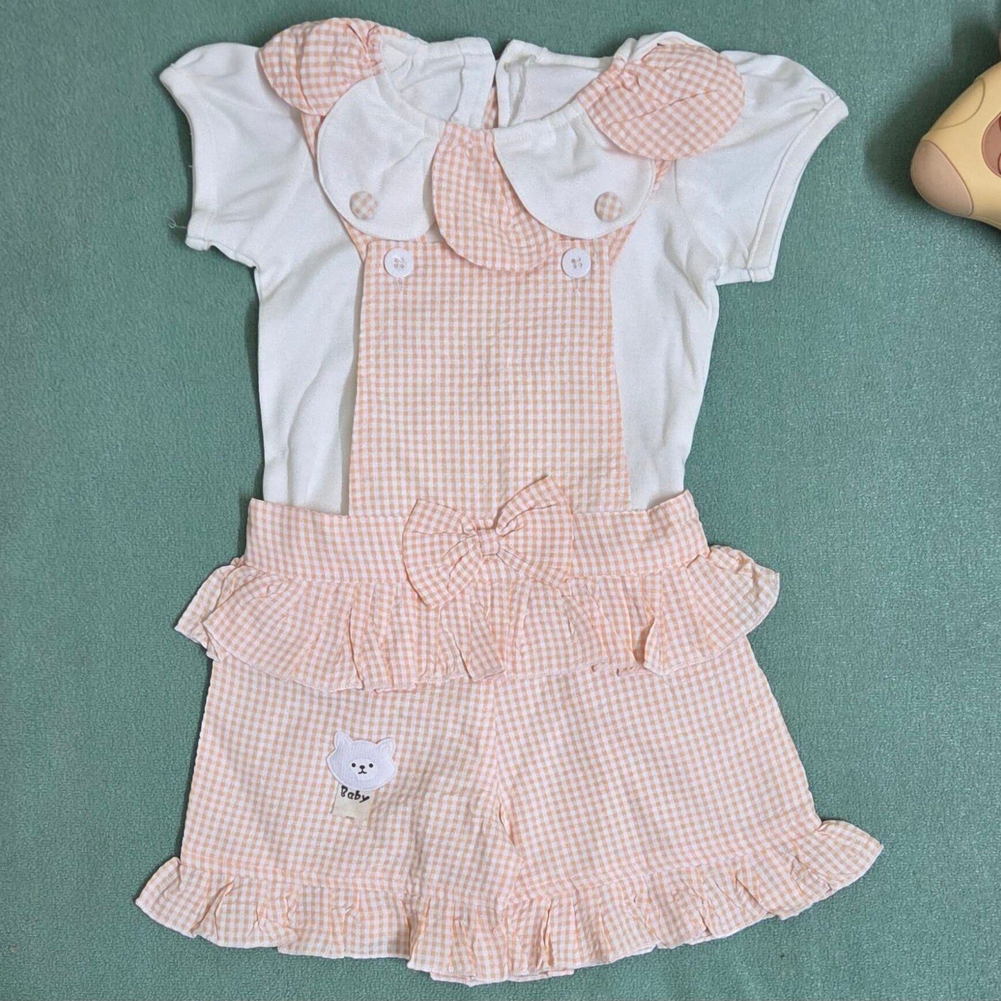 Children's dress with checkered pattern and white shirt on a green background