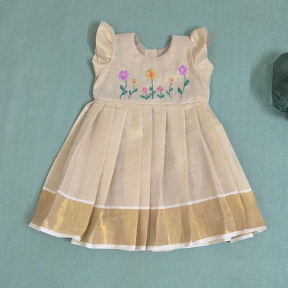 onam Beige dress with floral embroidery and kasavu border on green bac ground