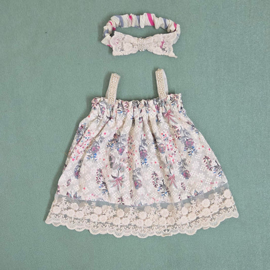 Floral dress with lace trim and matching headband on a green background