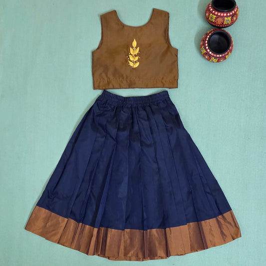 Brown top with gold embroidery and navy blue skirt on a light green background
