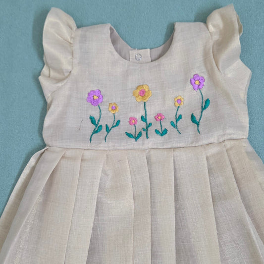 Onam girls' frock with floral embroidery and kasavu border.