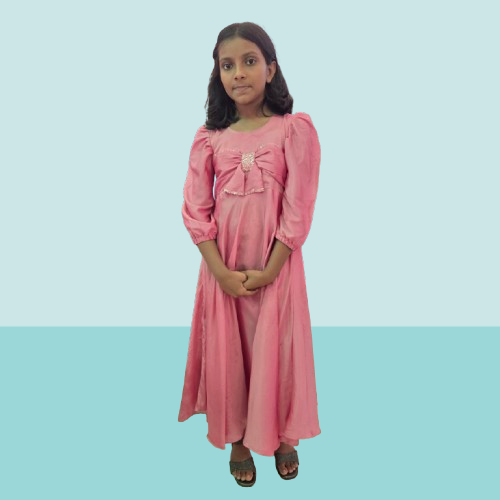 Young girl wearing a pink dress with a bow detail on a light blue background